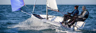 First 14 med spinnaker och två seglare, sedd akterifrån.