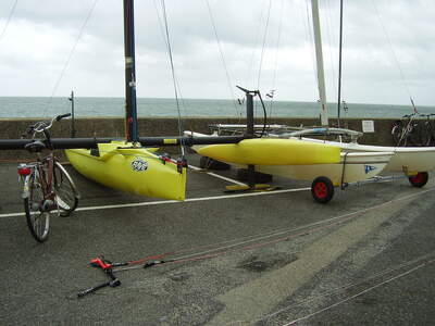 WindRider Rave, hydrofoilassisterad trimaran sedd från sidan med gulmålade skrov och komplett rigg. Foto: Kamel15