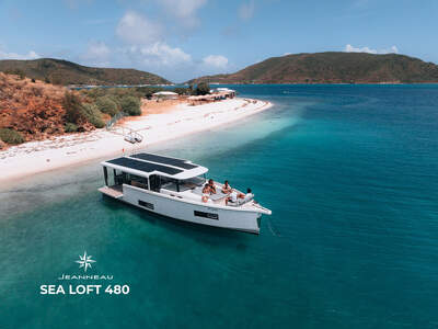 Jeanneau Sea Loft 480 vid en sandstrand och turkost vatten.