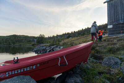 Röd Pioner 8 Mini dragen över fjällterräng vid en sjö; modellnamnet syns på skrovsidan.